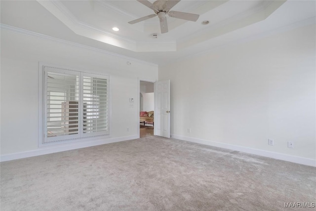 carpeted spare room featuring a raised ceiling, ornamental molding, and ceiling fan