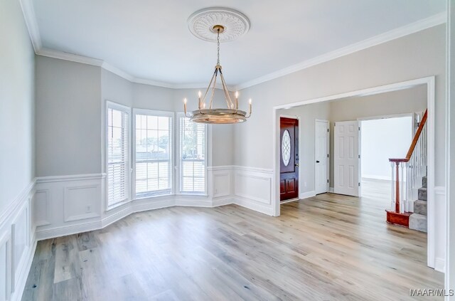 unfurnished dining area with an inviting chandelier, light hardwood / wood-style flooring, and ornamental molding