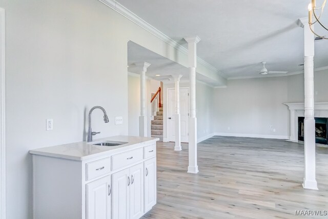 kitchen with ceiling fan, white cabinetry, light hardwood / wood-style flooring, crown molding, and sink