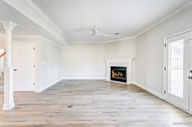 unfurnished living room featuring ornamental molding, a high end fireplace, light hardwood / wood-style flooring, and decorative columns