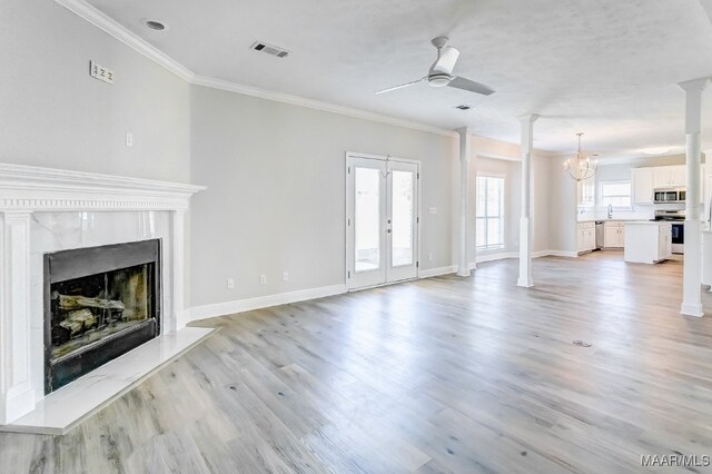 unfurnished living room with french doors, ornamental molding, ceiling fan with notable chandelier, and light wood-type flooring