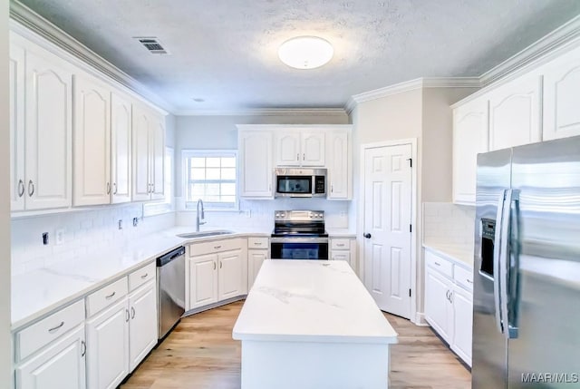 200 Mcrae Rd, Deatsville, AL 36022 - kitchen with appliances with stainless steel finishes, a sink, white cabinetry, decorative backsplash, and a center island