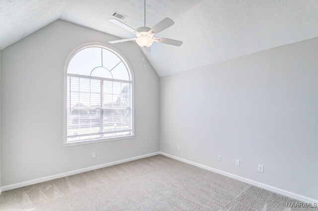 carpeted empty room featuring vaulted ceiling, a textured ceiling, a wealth of natural light, and ceiling fan