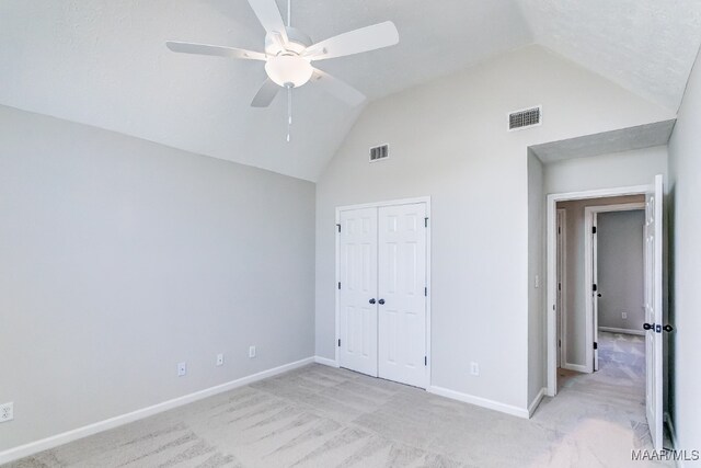 unfurnished bedroom featuring a closet, ceiling fan, light carpet, and vaulted ceiling