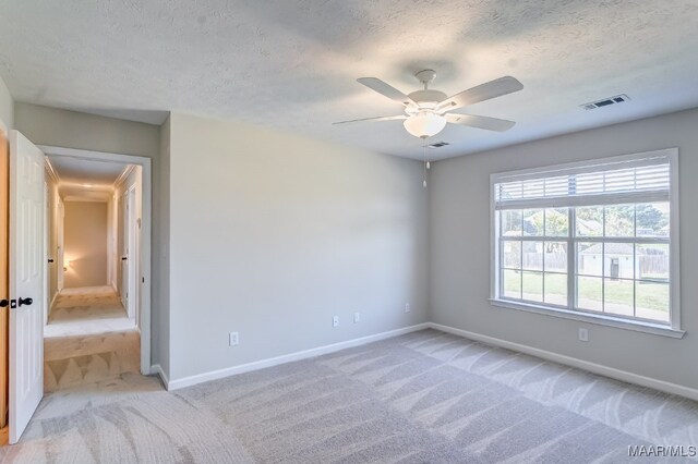 carpeted spare room with ceiling fan and a textured ceiling