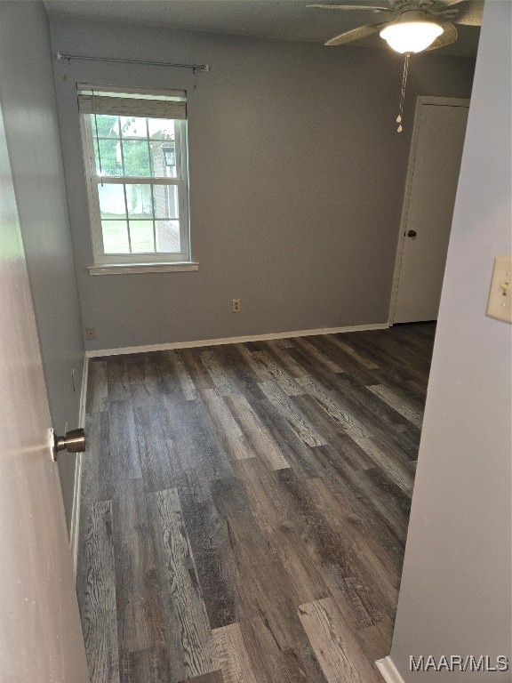 empty room with dark wood-type flooring and ceiling fan