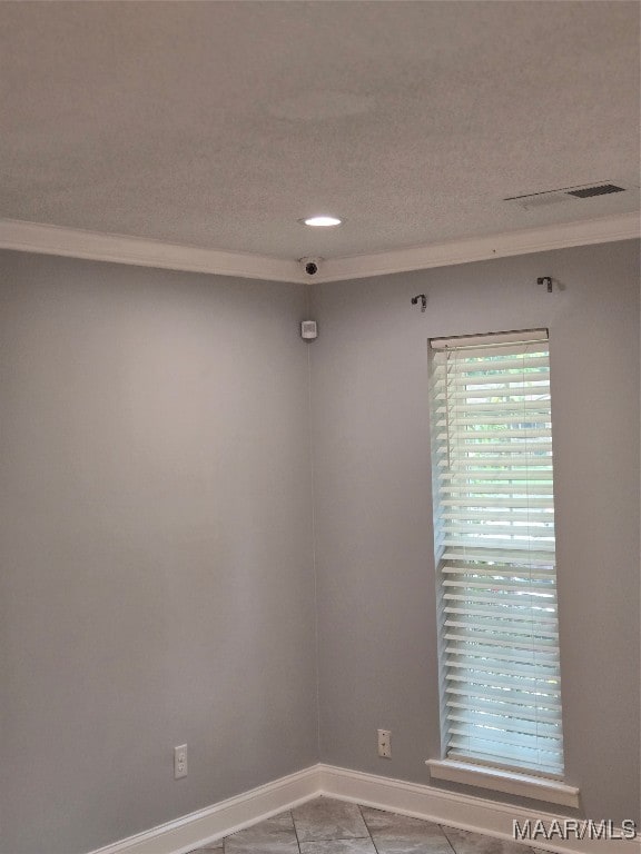 empty room with a textured ceiling, light tile patterned flooring, and ornamental molding