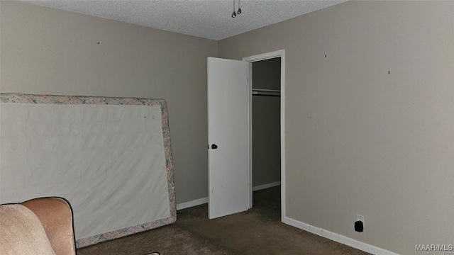 unfurnished bedroom with dark carpet, a closet, and a textured ceiling