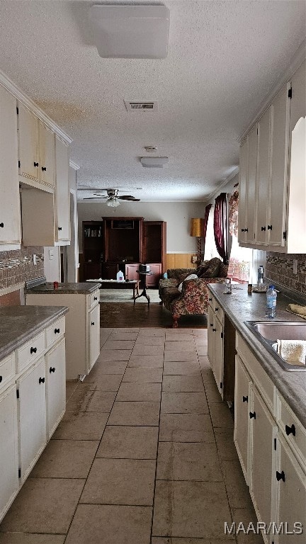 kitchen featuring ceiling fan, backsplash, and white cabinets