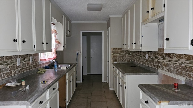 kitchen with tasteful backsplash, white cabinetry, crown molding, sink, and tile patterned flooring