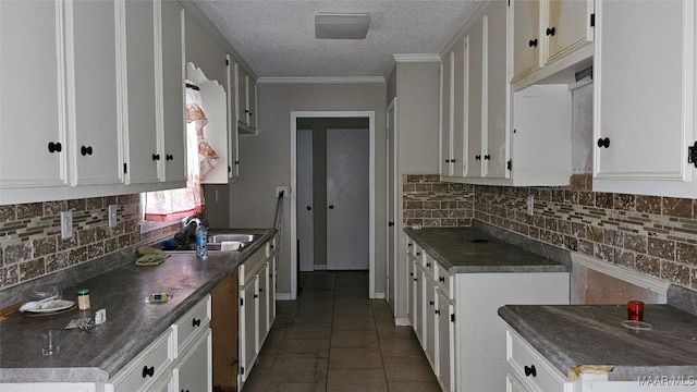 kitchen with tasteful backsplash, white cabinetry, sink, tile patterned flooring, and ornamental molding