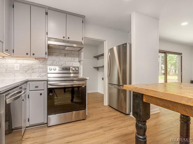 kitchen featuring tasteful backsplash, light wood-style flooring, under cabinet range hood, appliances with stainless steel finishes, and light countertops