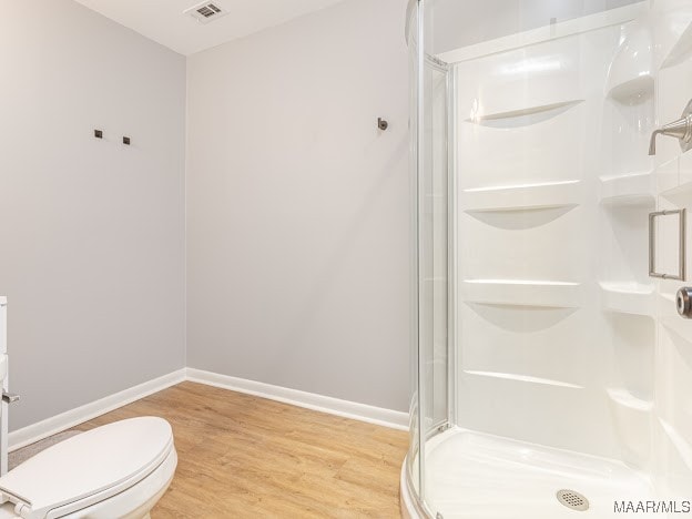 bathroom featuring toilet, hardwood / wood-style floors, and a shower with shower door