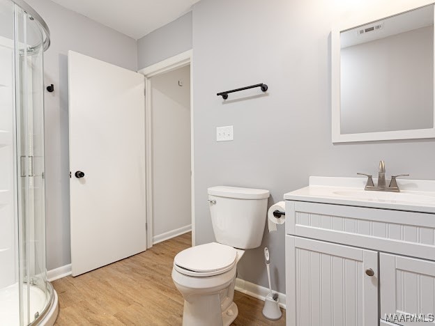 bathroom featuring vanity, toilet, walk in shower, and wood-type flooring