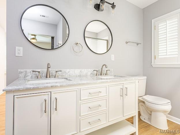 full bath with visible vents, wood finished floors, toilet, and a sink