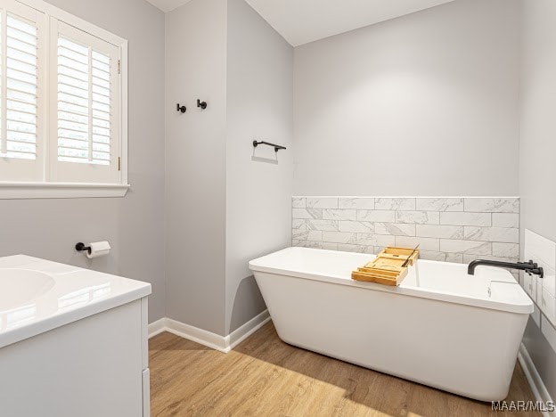 bathroom with vanity, hardwood / wood-style flooring, and a bath