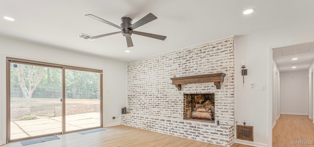 unfurnished living room featuring light hardwood / wood-style floors, a brick fireplace, and ceiling fan