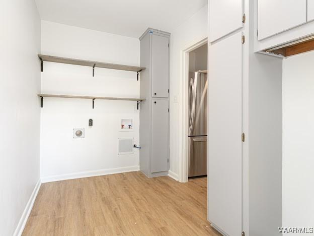 washroom with hookup for an electric dryer, light wood finished floors, cabinet space, hookup for a washing machine, and baseboards