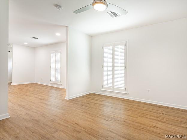 spare room featuring light wood-style floors, ceiling fan, plenty of natural light, and baseboards