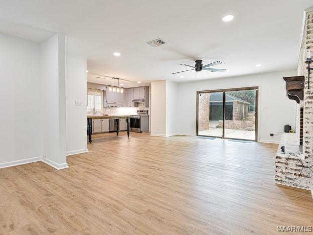 unfurnished living room with baseboards, recessed lighting, and light wood-style floors