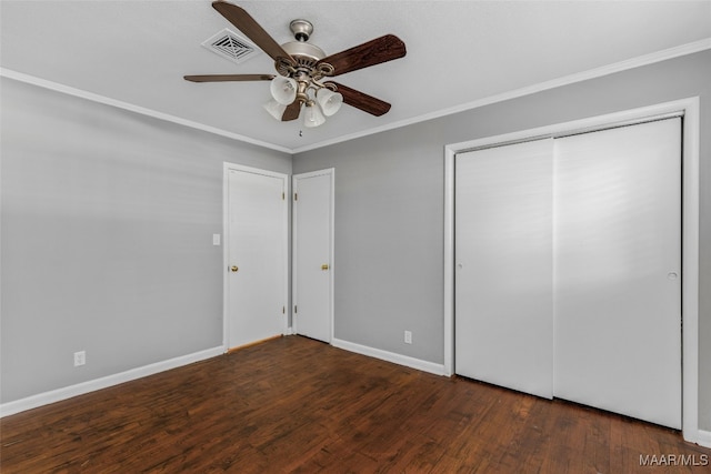 unfurnished bedroom with ornamental molding, dark wood-type flooring, a closet, and ceiling fan