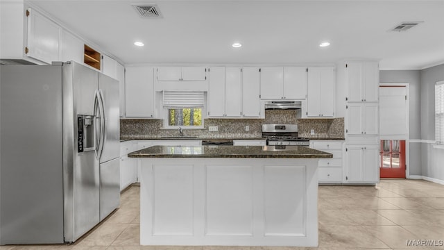 kitchen featuring a center island, stainless steel appliances, white cabinets, and dark stone counters