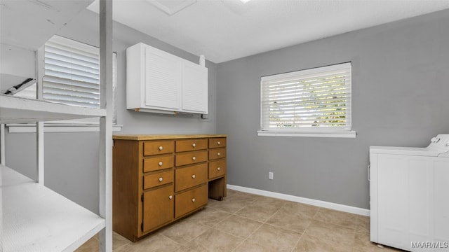 interior space featuring washer and dryer, cabinets, and light tile patterned floors