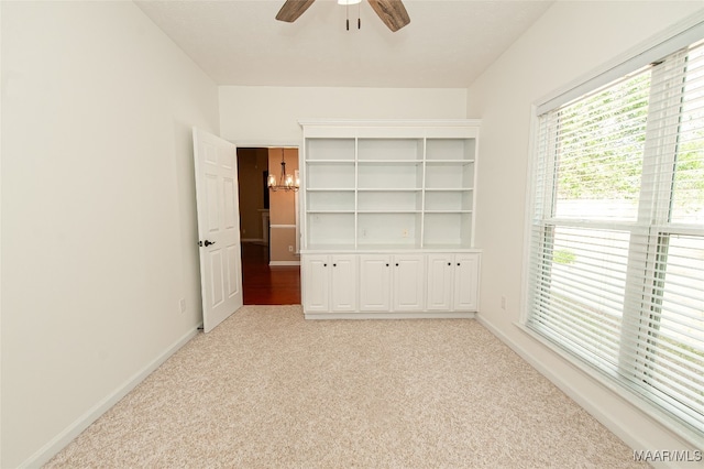 unfurnished bedroom with light colored carpet and ceiling fan with notable chandelier