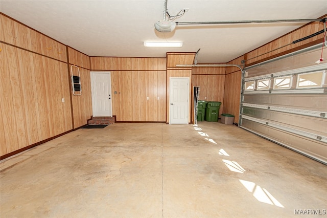 garage featuring a garage door opener and wooden walls