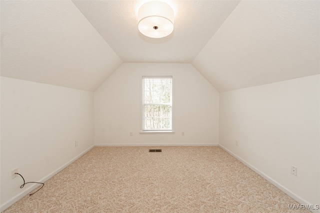 bonus room featuring a textured ceiling, light colored carpet, and vaulted ceiling