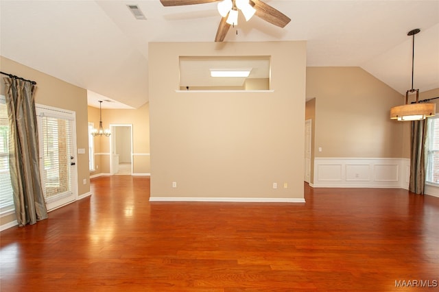 unfurnished living room featuring high vaulted ceiling, dark wood-type flooring, ceiling fan with notable chandelier, and a wealth of natural light