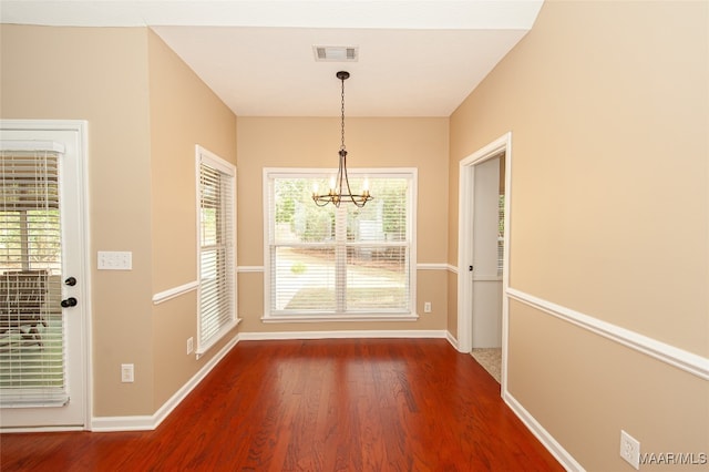 unfurnished dining area with wood-type flooring and a chandelier