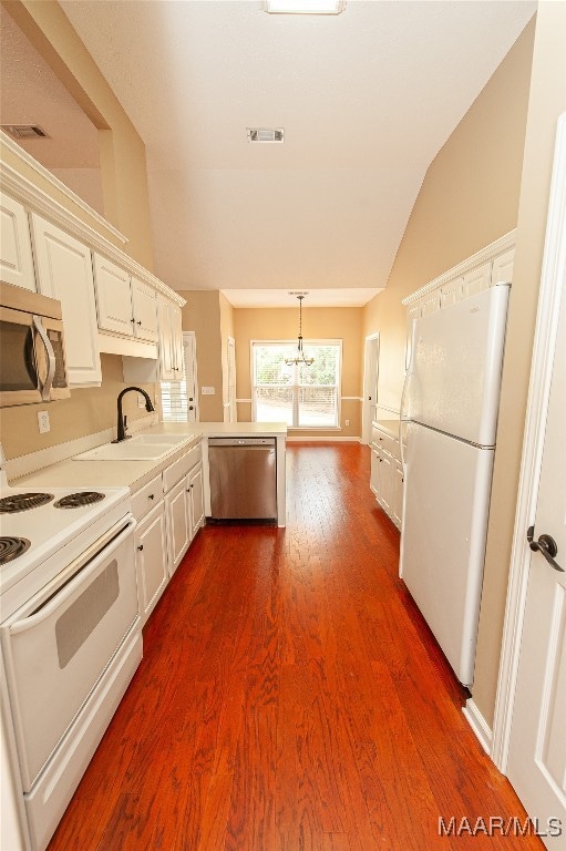 kitchen with white cabinets, dark hardwood / wood-style flooring, appliances with stainless steel finishes, vaulted ceiling, and sink