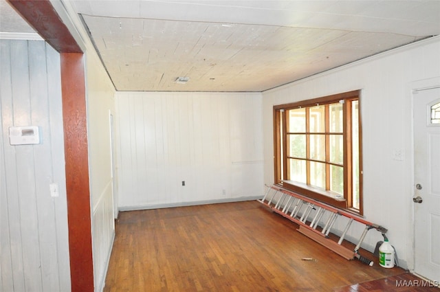 unfurnished room with hardwood / wood-style floors and wooden walls