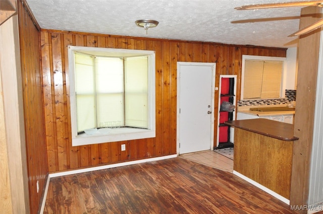 interior space with wood walls, hardwood / wood-style floors, a textured ceiling, and ceiling fan