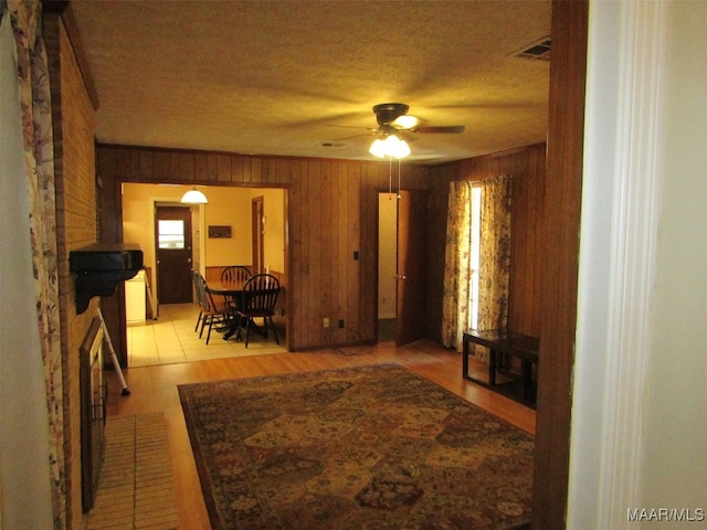 living room featuring ceiling fan, light tile patterned floors, and wooden walls