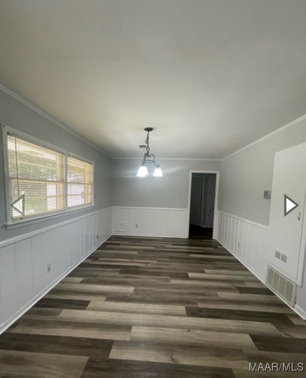 empty room featuring a notable chandelier, dark hardwood / wood-style floors, and crown molding