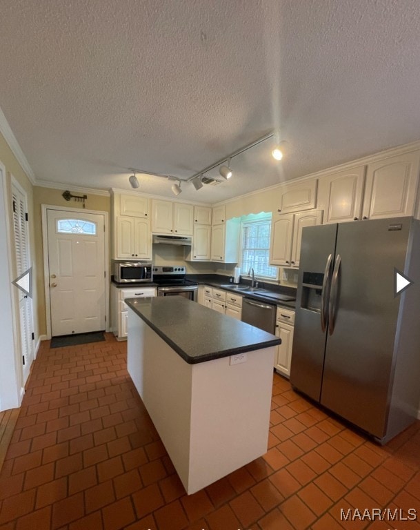 kitchen featuring ornamental molding, a textured ceiling, stainless steel appliances, and dark tile patterned floors