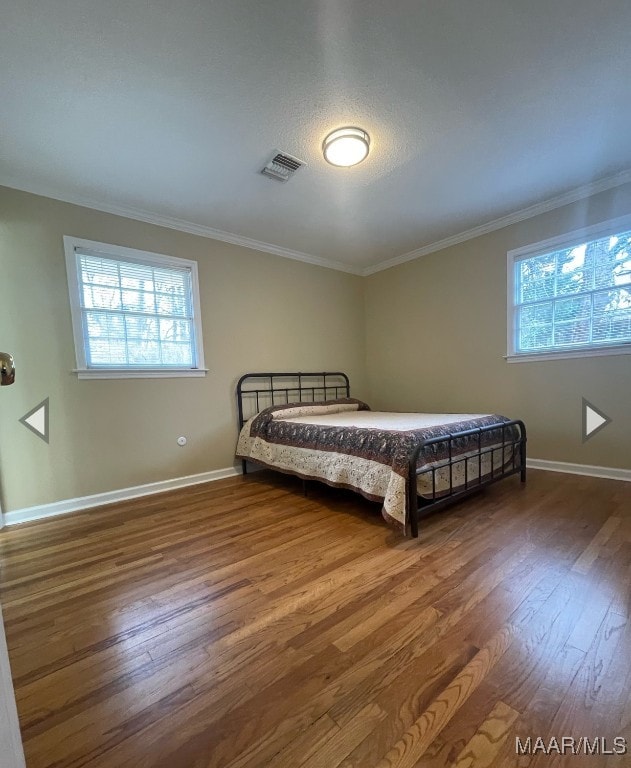 bedroom with crown molding and dark wood-type flooring