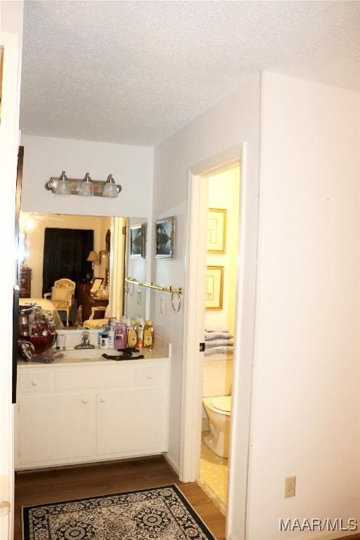 bathroom featuring toilet, vanity, a textured ceiling, and hardwood / wood-style flooring