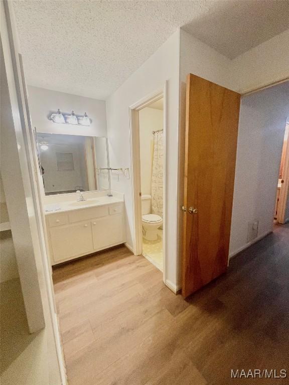 bathroom featuring hardwood / wood-style floors, vanity, a textured ceiling, and toilet