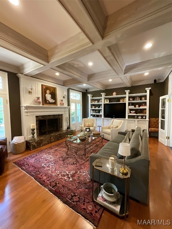 living room featuring beam ceiling, a premium fireplace, and hardwood / wood-style flooring