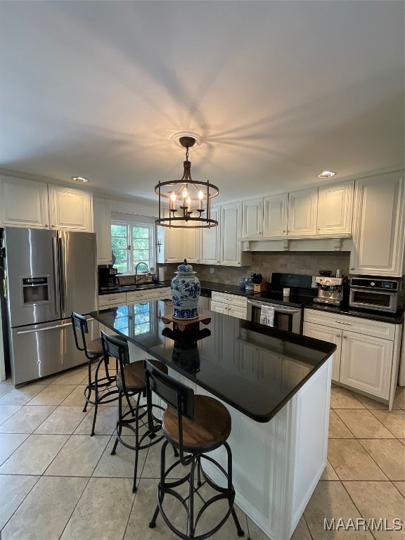 kitchen with pendant lighting, white cabinetry, stainless steel appliances, and light tile patterned floors