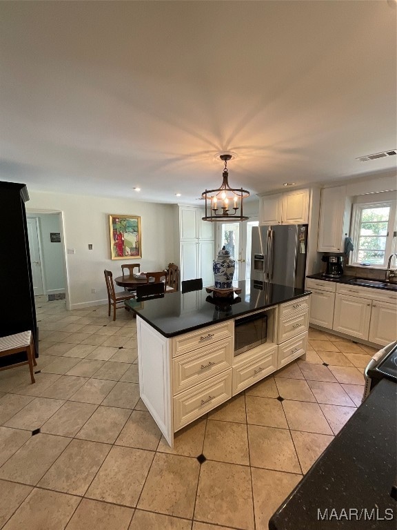 kitchen featuring stainless steel fridge, white cabinets, light tile patterned floors, built in microwave, and sink