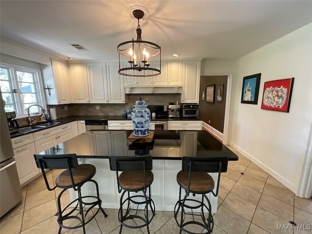 kitchen with sink, white cabinetry, decorative light fixtures, and backsplash