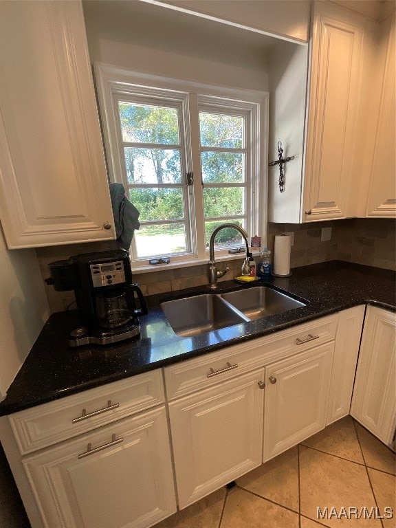 kitchen with backsplash, light tile patterned flooring, sink, and white cabinets