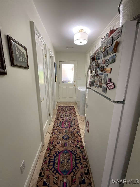 hallway featuring washing machine and dryer and light tile patterned floors