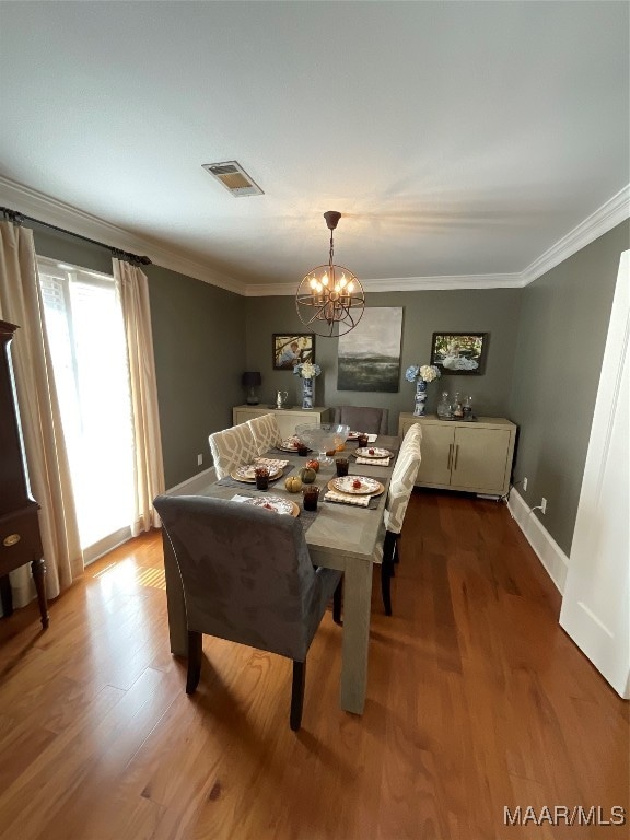 dining area with crown molding, wood-type flooring, and a chandelier