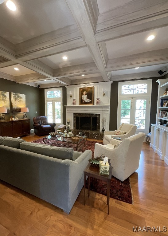 living room featuring light hardwood / wood-style flooring, a high end fireplace, coffered ceiling, and a wealth of natural light