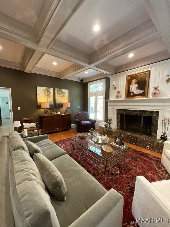 living room with beam ceiling, coffered ceiling, a premium fireplace, and hardwood / wood-style floors